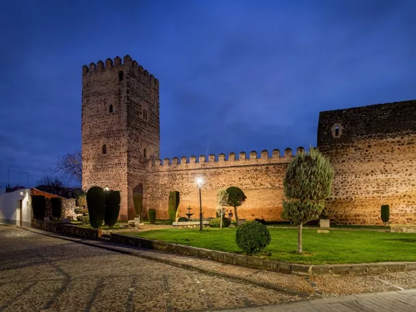 Muralla y torre de piedra iluminadas al atardecer