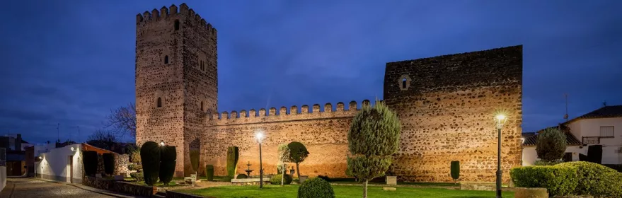 Muralla y torre de piedra iluminadas al atardecer