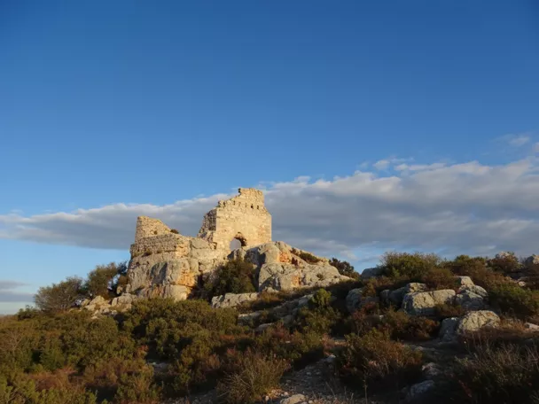 Antiguas murallas coronando una elevación bajo cielo azul.