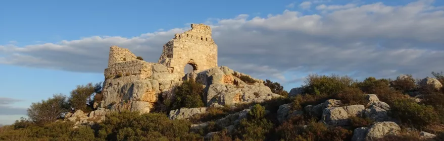 Antiguas murallas coronando una elevación bajo cielo azul.