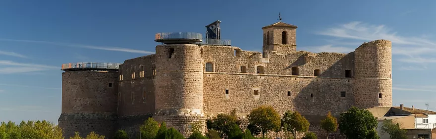 Castillo de piedra con torres circulares sobre colina