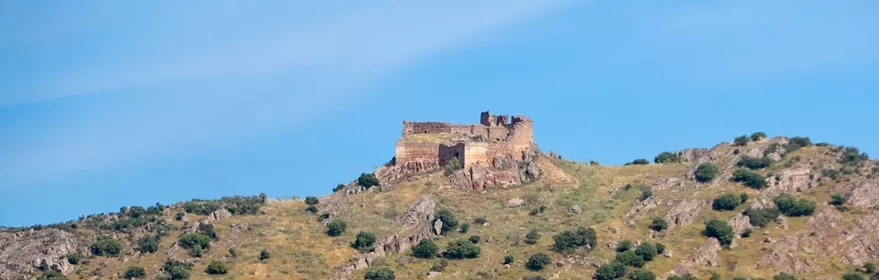 Fortaleza en ruinas sobre colina cubierta de matorral