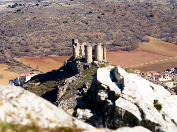 Ruinas de castillo sobre colina rodeada de campos.
