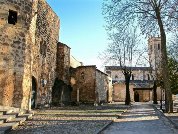 Plaza empedrada junto a iglesia y muralla.