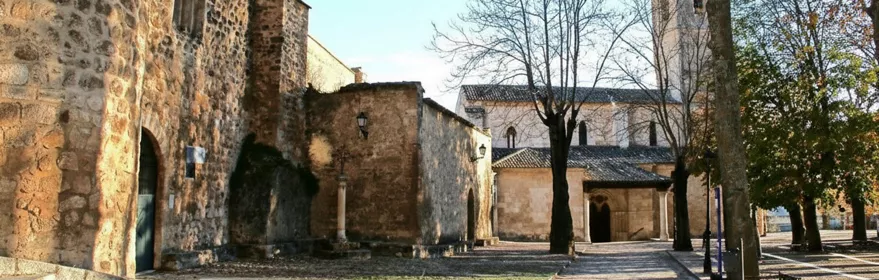 Plaza empedrada junto a iglesia y muralla.