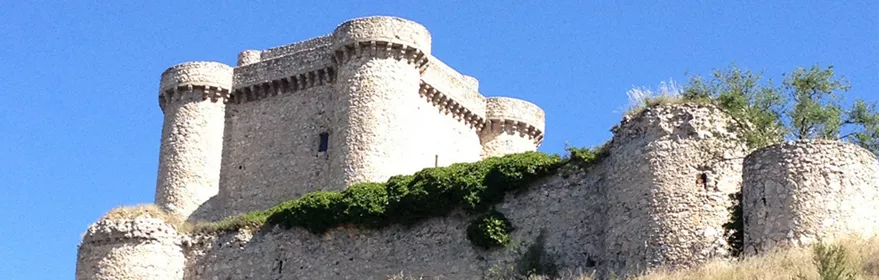 Castillo medieval de piedra sobre colina en paisaje manchego