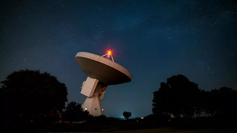 Radiotelescopio bajo cielo estrellado.