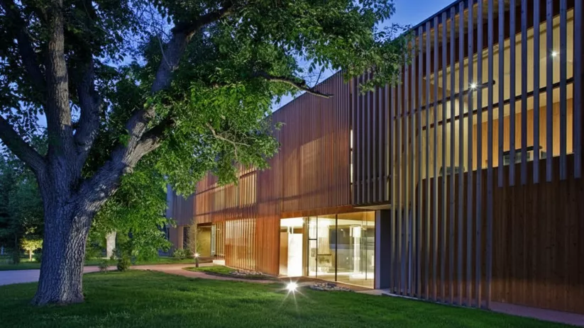 Edificio moderno de madera iluminado al anochecer.