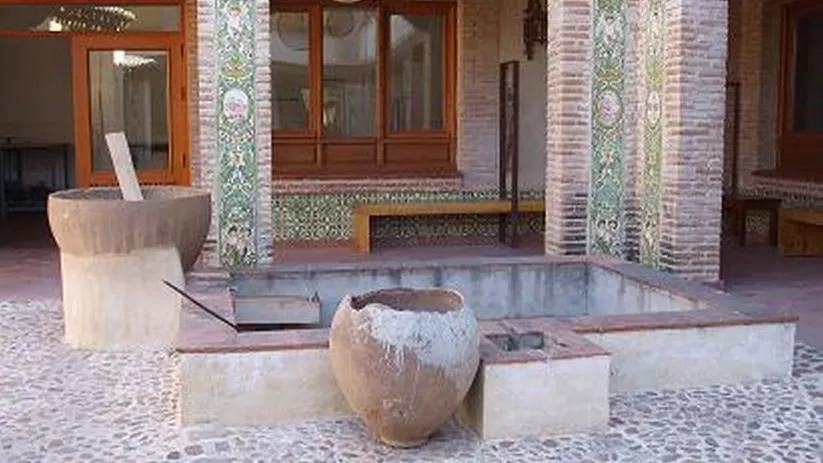Patio con columnas decoradas con azulejos y pila de piedra central.