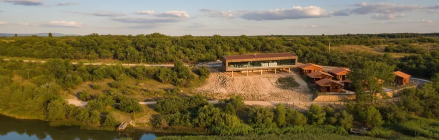 Edificio moderno junto a laguna y bosque.