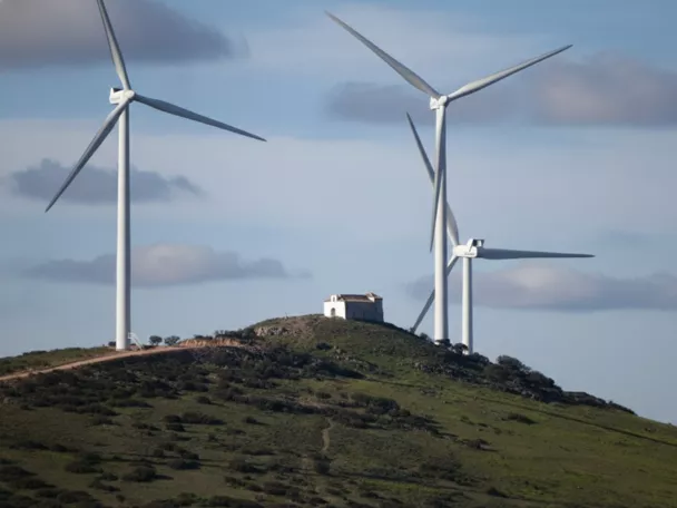 Aerogeneradores sobre colina verde con edificación aislada