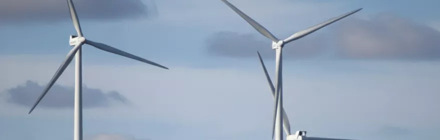 Aerogeneradores sobre colina verde con edificación aislada