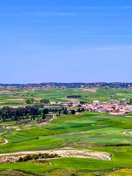 Vista panorámica de campos verdes y núcleo rural desde una colina