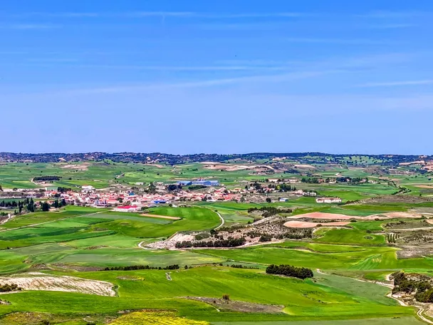 Vista panorámica de campos verdes y núcleo rural desde una colina
