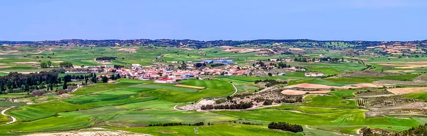 Vista panorámica de campos verdes y núcleo rural desde una colina