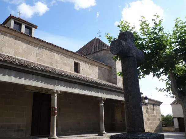 Pórtico de piedra con columnas y cruz de granito en primer plano