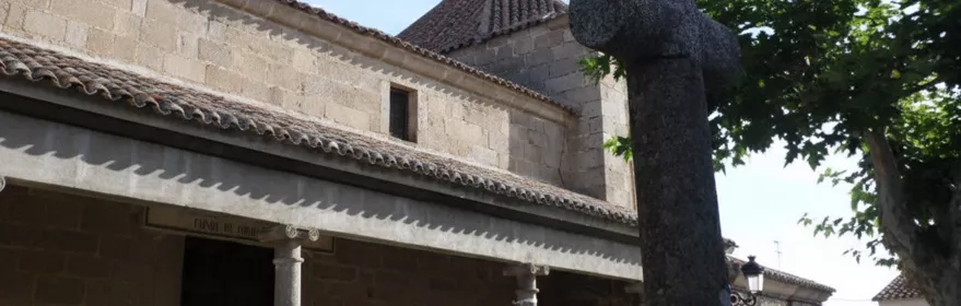 Pórtico de piedra con columnas y cruz de granito en primer plano