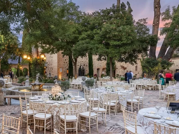 Patio ajardinado con mesas decoradas alrededor de una fuente.
