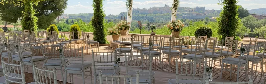 Espacio para ceremonia al aire libre con sillas y pérgola cubierta de vegetación.