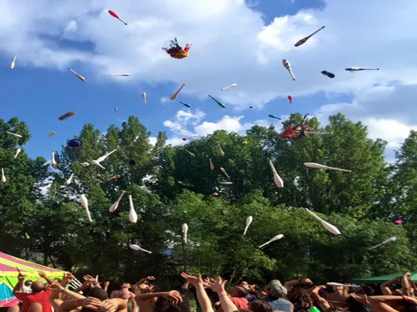 Lanzamiento de mazas sobre una carpa de circo al aire libre con público celebrando