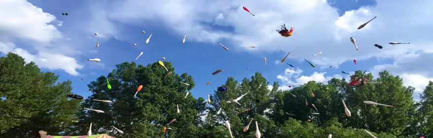 Lanzamiento de mazas sobre una carpa de circo al aire libre con público celebrando