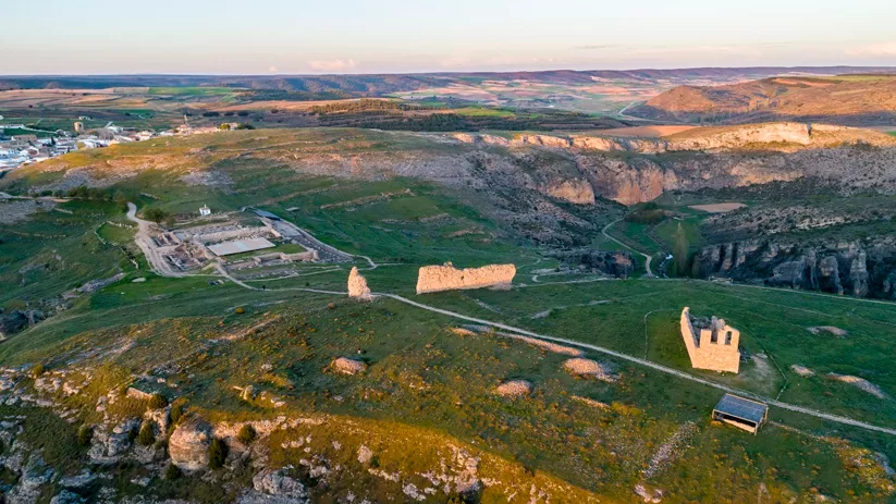 Vista aérea de un asentamiento antiguo en colina con restos de murallas.