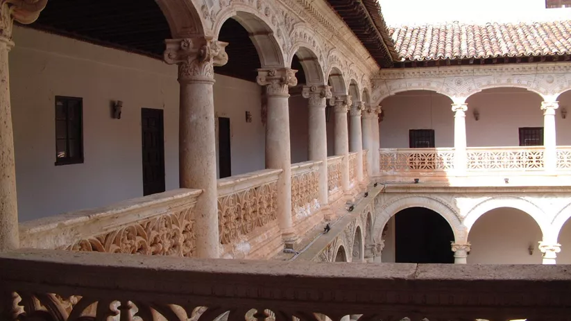 Galería superior con columnas y balaustrada tallada.