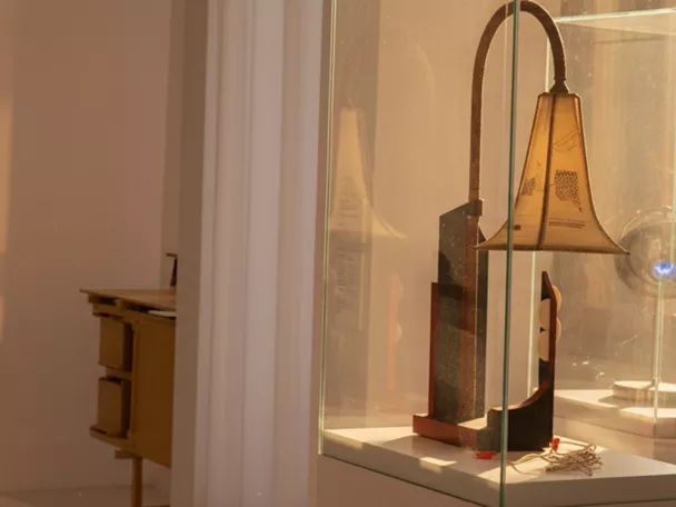 Vitrina con pieza artística iluminada en sala blanca.