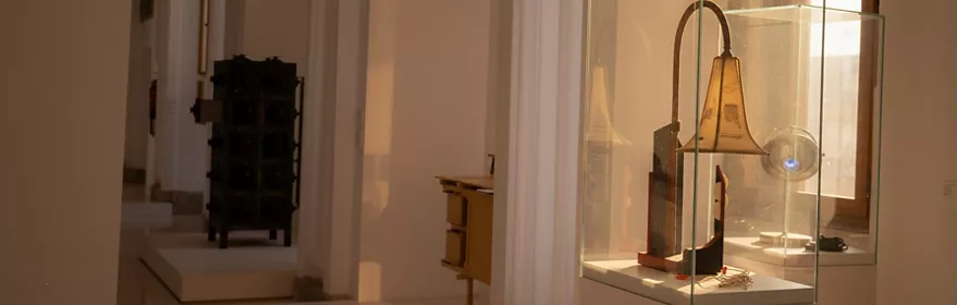 Vitrina con pieza artística iluminada en sala blanca.