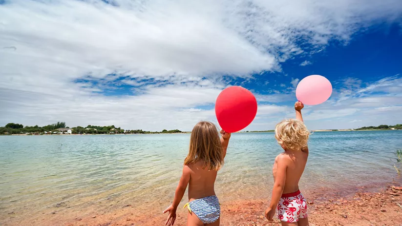 Dos niños jugando junto al agua en un entorno natural.