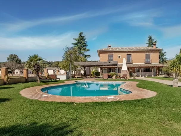 Casa rural con piscina rodeada de césped y palmeras