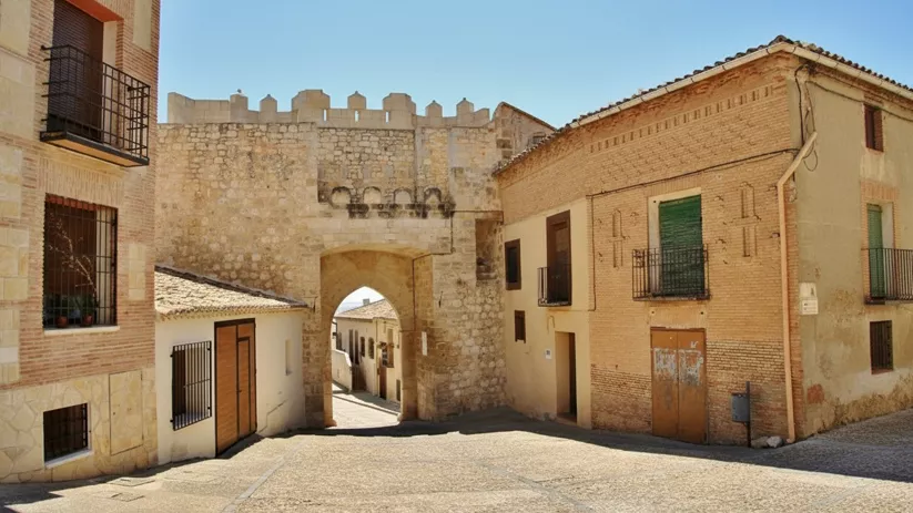 Calle empedrada con arco de piedra medieval.