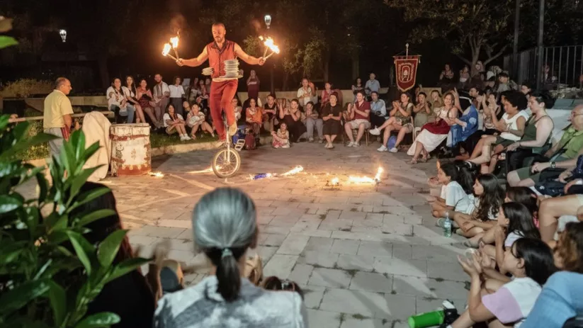 Artista con antorchas sobre monociclo en actuación nocturna