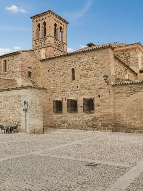 Fachada de iglesia de ladrillo y piedra frente a plaza empedrada