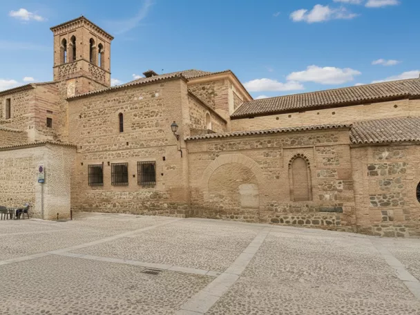 Fachada de iglesia de ladrillo y piedra frente a plaza empedrada