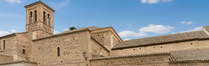 Fachada de iglesia de ladrillo y piedra frente a plaza empedrada