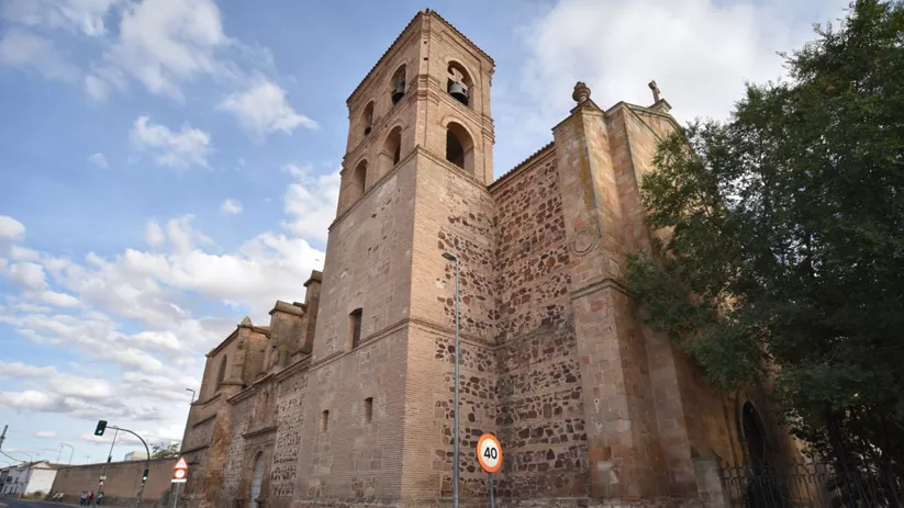 Fachada de iglesia de piedra con torre y contrafuertes.