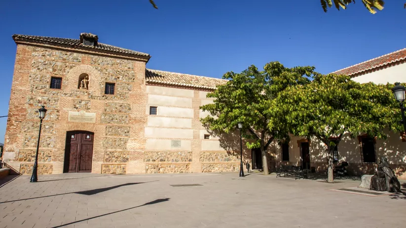 Plaza con edificio histórico de piedra y árboles