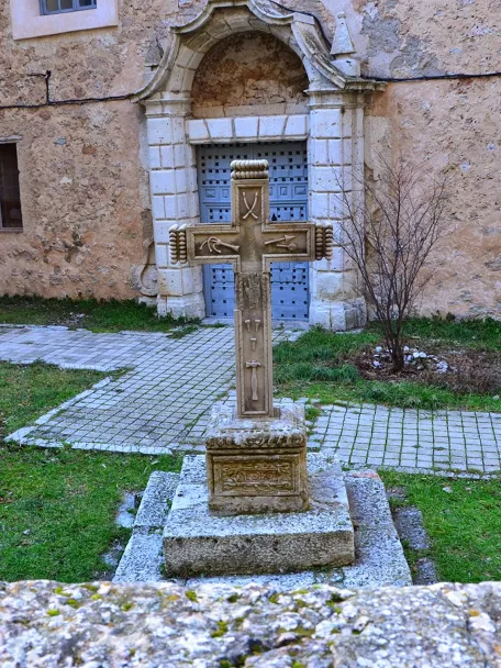 Cruz de piedra en patio con fachada histórica