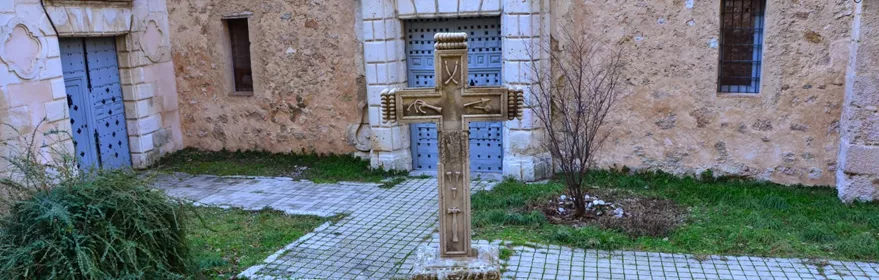 Cruz de piedra en patio con fachada histórica