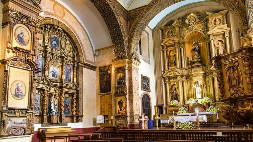 Interior de iglesia con retablos dorados y altar decorado.