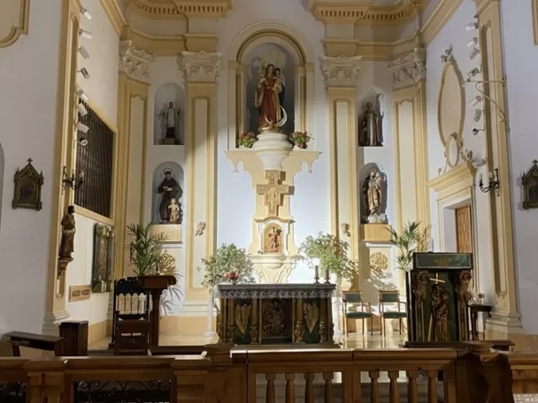 Interior de iglesia con altar y retablos laterales.