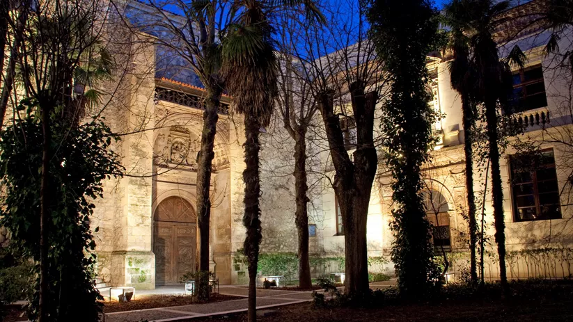 Convento monumental iluminado de noche en parque.
