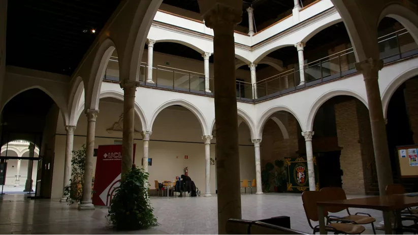 Patio interior con arcos blancos, columnas y mesas bajo galería cubierta.
