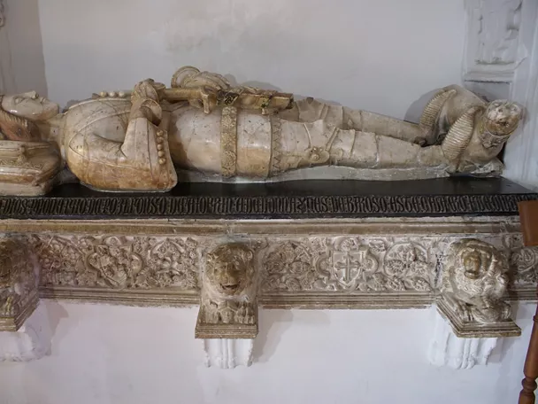 Sepulcro de mármol con figura yacente sobre base esculpida con relieves.