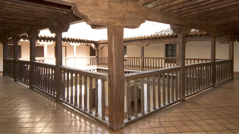 Galería superior de patio con estructura y barandillas de madera.