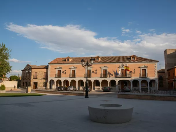 Plaza amplia con edificio porticado y fachada institucional