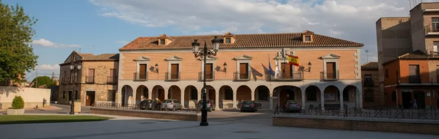 Plaza amplia con edificio porticado y fachada institucional