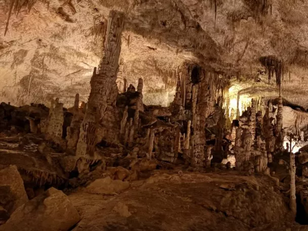 Gran sala subterránea con abundantes estalactitas y estalagmitas iluminadas.