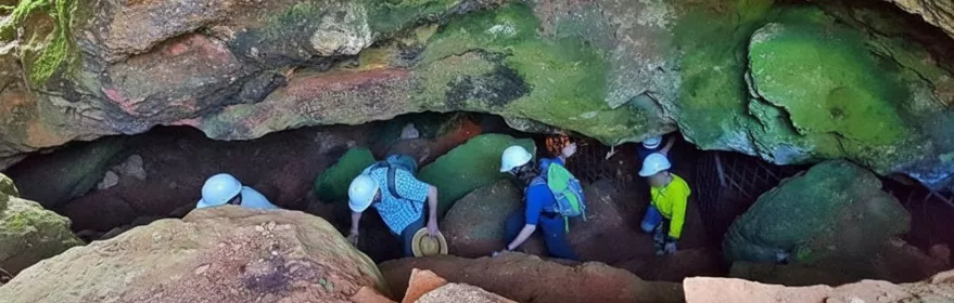 Grupo descendiendo por una abertura de cueva cubierta de musgo.